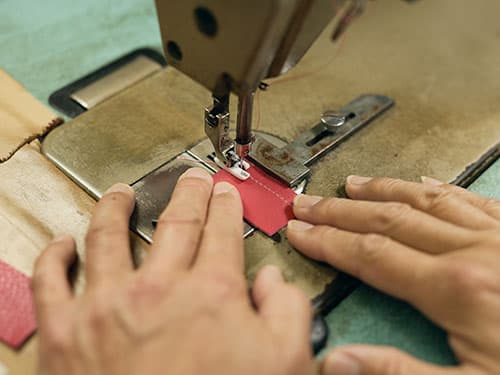 工業用ミシンで生地を縫製する職人の手元
